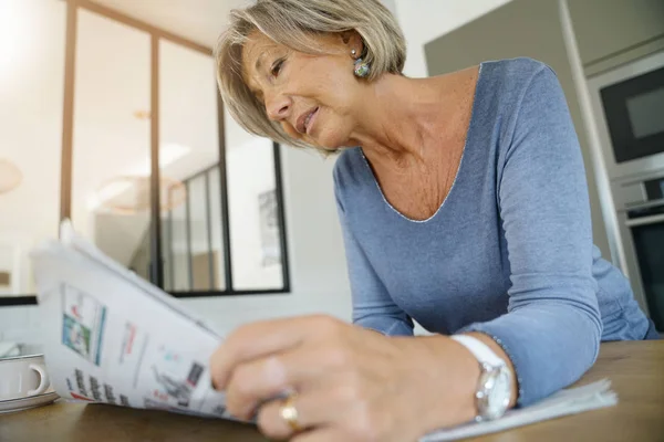 Ανώτερος Γυναίκα Στο Σπίτι Διαβάζοντας Εφημερίδα Στην Κουζίνα Στο Σπίτι — Φωτογραφία Αρχείου