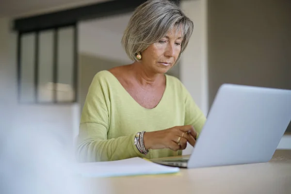 Ανώτερος γυναίκα στο σπίτι χρησιμοποιώντας φορητό υπολογιστή — Φωτογραφία Αρχείου