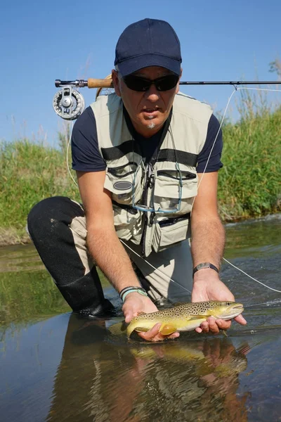 Pêcheur attrapant la truite brune — Photo