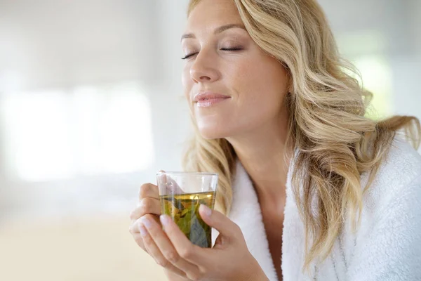 Woman in bathrobe drinking infusion — Stock Photo, Image