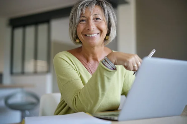 Mujer mayor en casa usando portátil — Foto de Stock