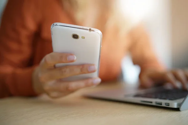 Vrouw aangesloten op smartphone en laptop — Stockfoto