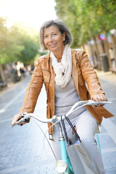 Anziano donna equitazione city bike Foto Stock