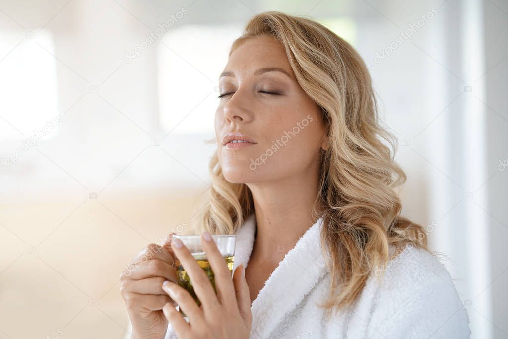 woman in bathrobe drinking infusion