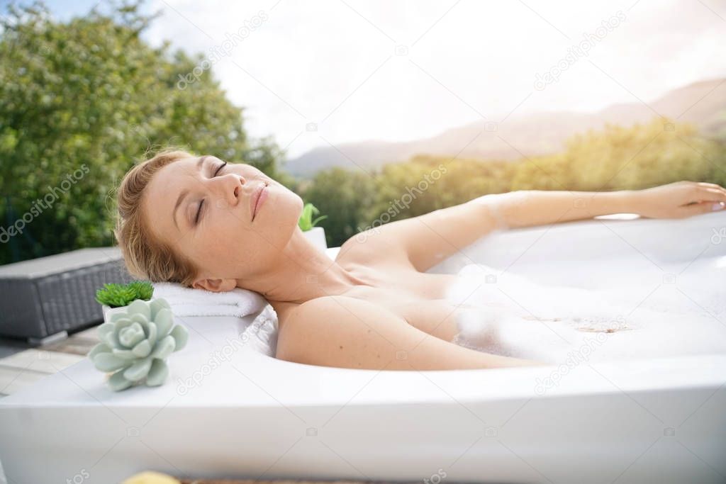 woman relaxing in outdoor bathtub