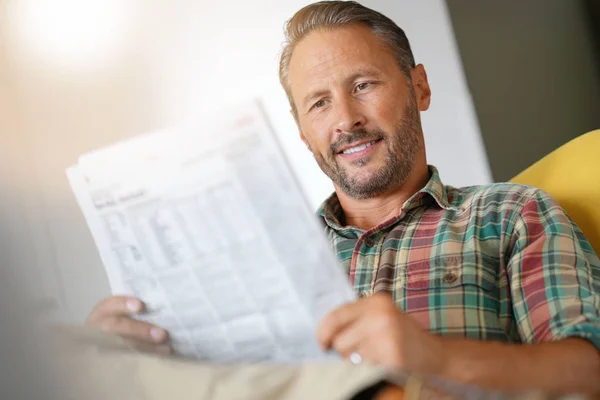 Een man die thuis kranten leest — Stockfoto