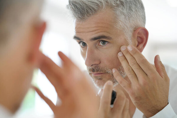 Middle-aged man applying cosmetic