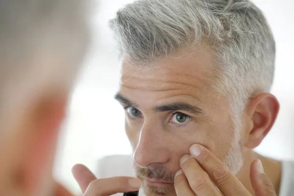 Homem de meia-idade aplicando cosméticos — Fotografia de Stock