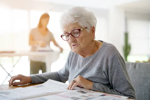 Gammal kvinna läsa tidningen — Stockfoto