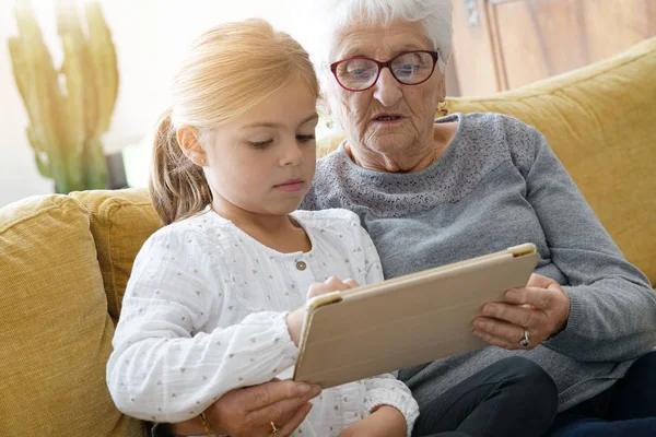 Девушка с бабушкой с помощью планшета — стоковое фото