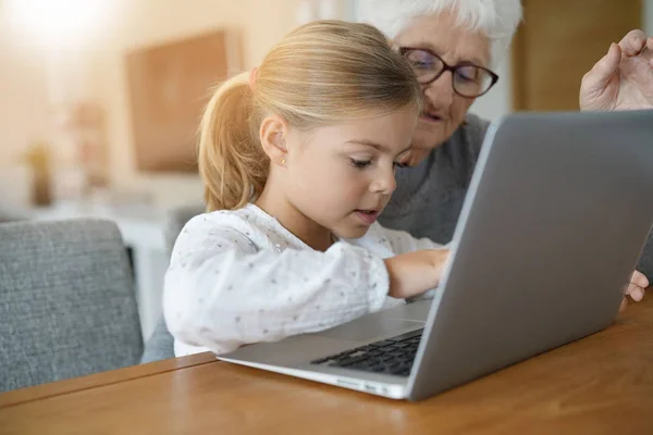 Flicka med mormor använder laptop — Stockfoto