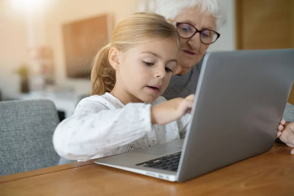 Flicka med mormor använder laptop — Stockfoto