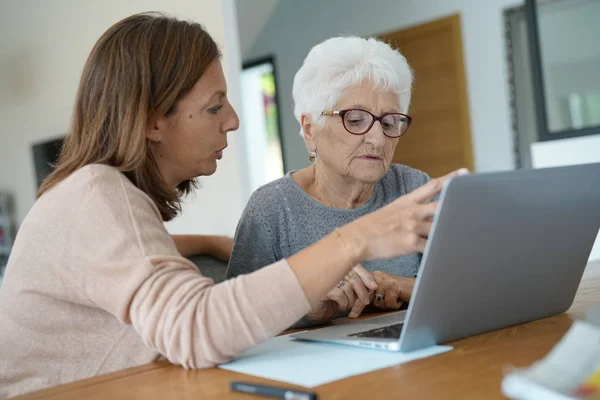 Kobieta za pomocą laptopa z pomocą homecarer — Zdjęcie stockowe
