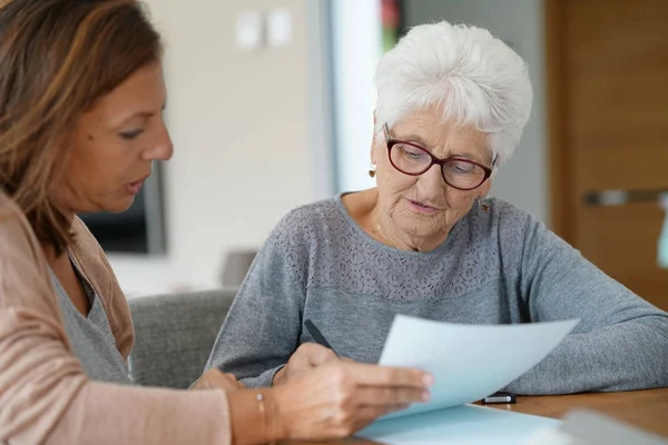 assistant helping elderly woman