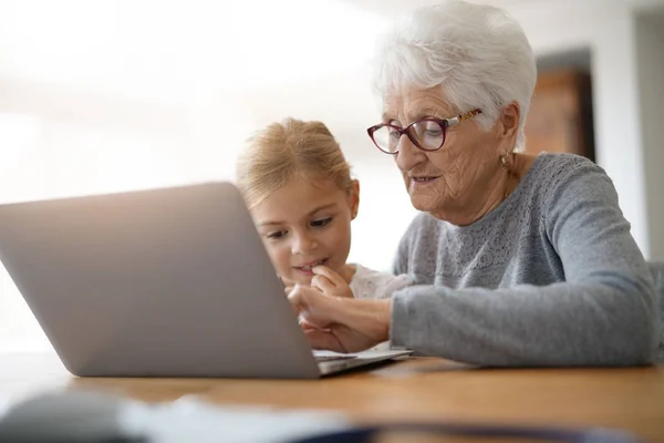 Dívka s babičkou pomocí přenosného počítače — Stock fotografie