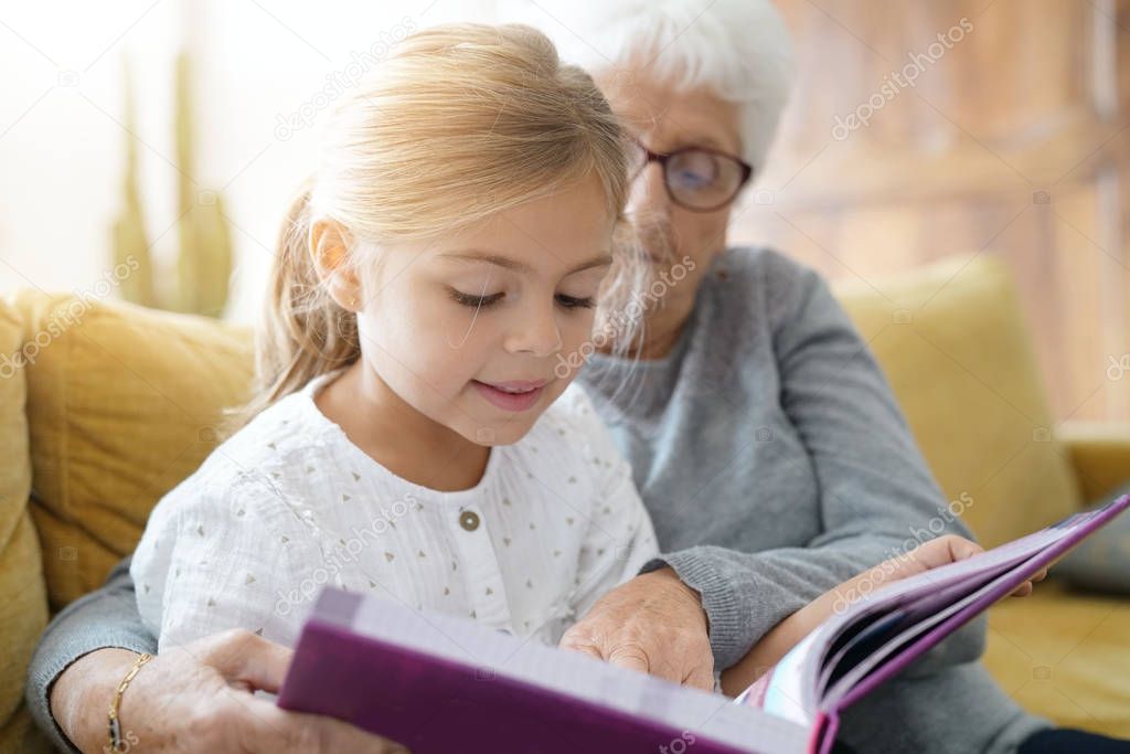 girl reading book with grandmother