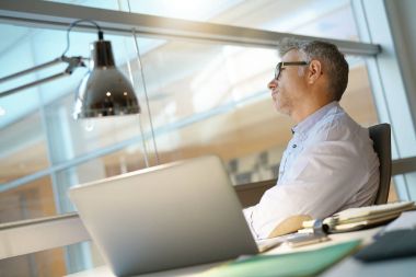 İşadamı ofiste dizüstü önünde düşünceli olmak