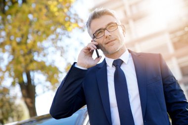 Arabanın dışında telefon ayakta konuşurken işadamı