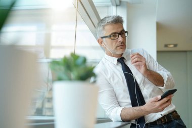 Cam kenarında duran ofiste telefonda konuşurken işadamı