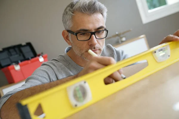 家具を組み立てるための木の部品を測定する男 — ストック写真