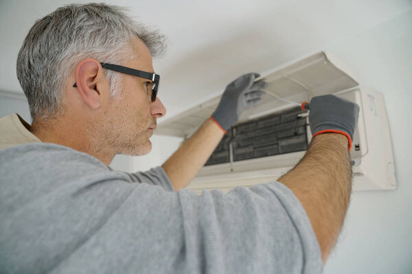Repairman fixing air conditioner unit