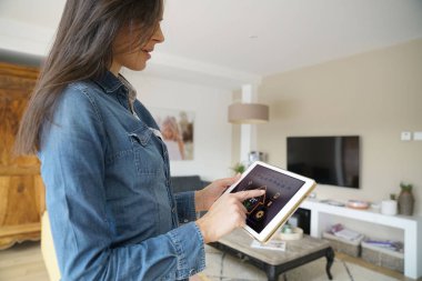 Dijital tablet üzerinde Uzaktan ev kontrol sistemi kullanan kadın