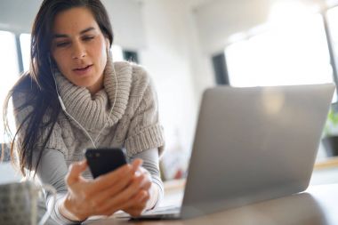 Kulaklık kullanarak dizüstü bilgisayar ve smartphone, bağlı kadın