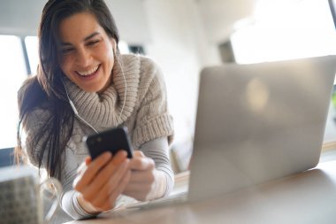 Kulaklık kullanarak dizüstü bilgisayar ve smartphone, bağlı kadın