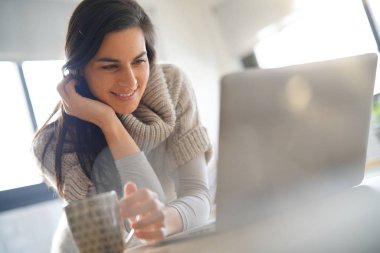 İnternete bağlı orta yaşlı bir kadın evde dizüstü bilgisayarla