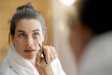 Kadının makyaj koyarak ayna önünde