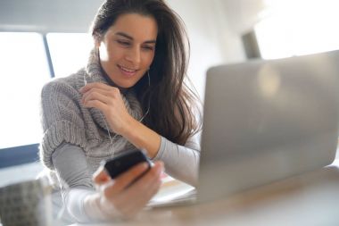 Kulaklık kullanarak dizüstü bilgisayar ve smartphone, bağlı kadın