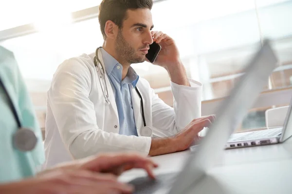 Joven Médico Oficina Trabajando Ordenador Portátil Hablando Por Teléfono —  Fotos de Stock