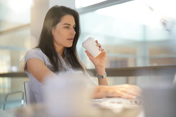 Businesswoman in office drinking coffee