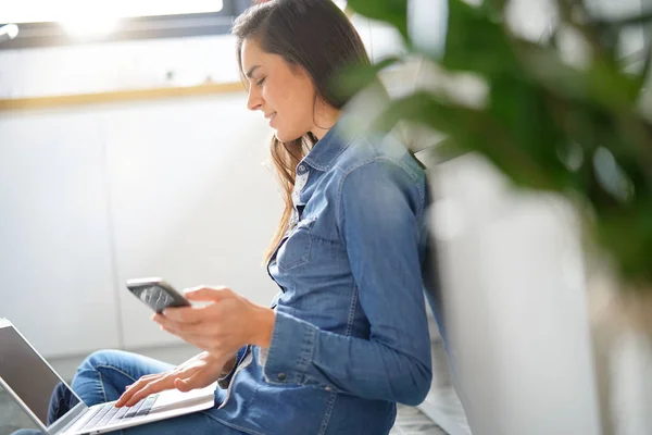 Brunette woman connected with laptop and smartphone