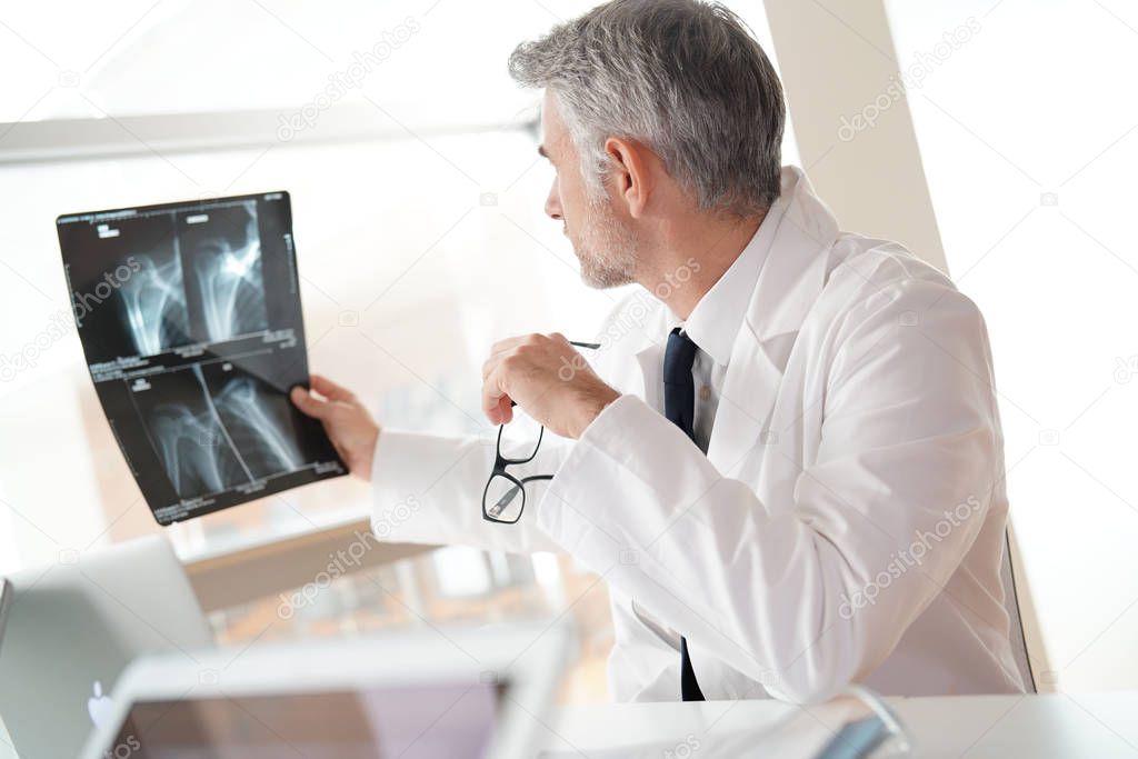 Mature doctor in office looking at Xray results
