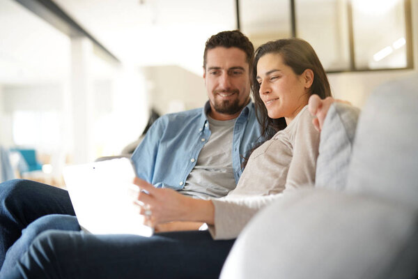 Couple relaxing on sofa and connected with digital tablet