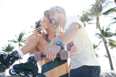 Genç trendy buz pateni insanlar Smartphone vasıl arıyorum