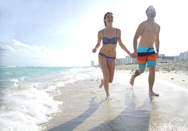 Tatilde kumlu bir plaj üzerinde çalışan genç Çift