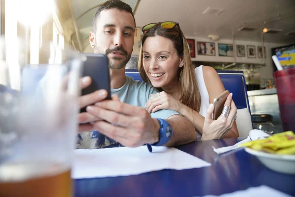 年轻夫妇连接智能手机在快餐店 — 图库照片