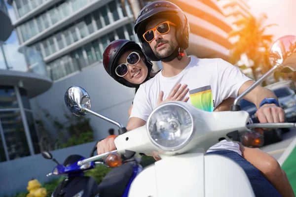 Cheerful couple riding scooter in Miami