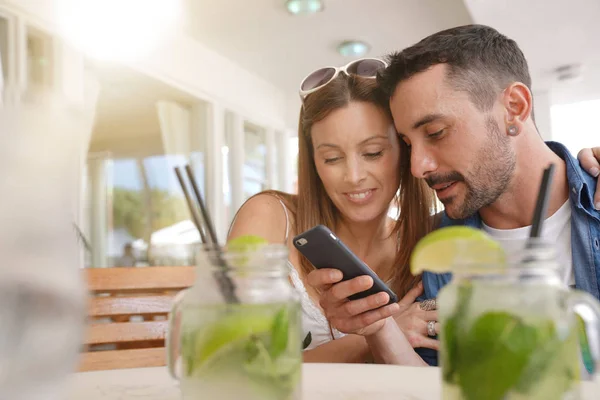 Young couple in bar connected with smartphone