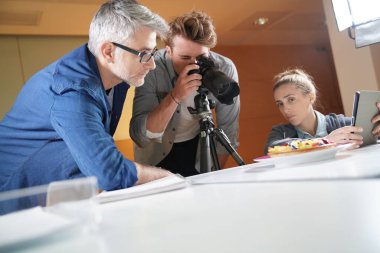 Photographer with apprentices in photo studio clipart