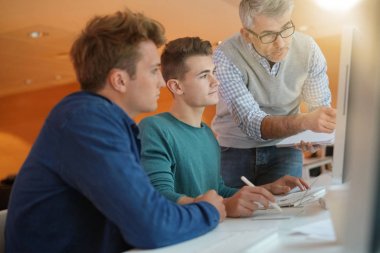 Öğretmen kontrol eden öğrenciler sınıfta çalışırlar