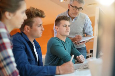 Öğretmen kontrol eden öğrenciler sınıfta çalışırlar