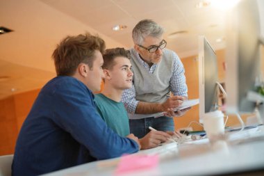 Öğretmen kontrol eden öğrenciler sınıfta çalışırlar