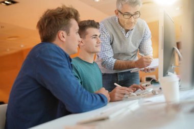 Öğretmen kontrol eden öğrenciler sınıfta çalışırlar