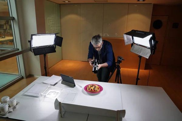 Upper view of photographer in studio shooting culinary pictures