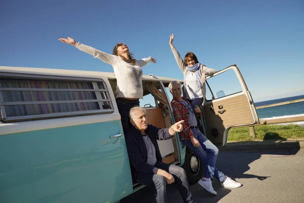 Senior people on a road trip with camper van enjoying stop by the sea