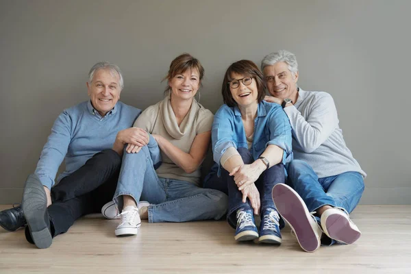 Grupa Szczęśliwych Ludzi Starszych Siedząc Podłodze Ścianie Białym Tle — Zdjęcie stockowe