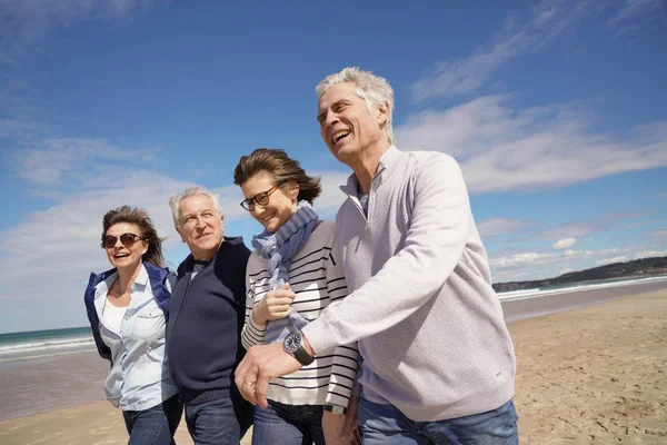 ビーチで一緒に歩いている高齢者のグループ — ストック写真